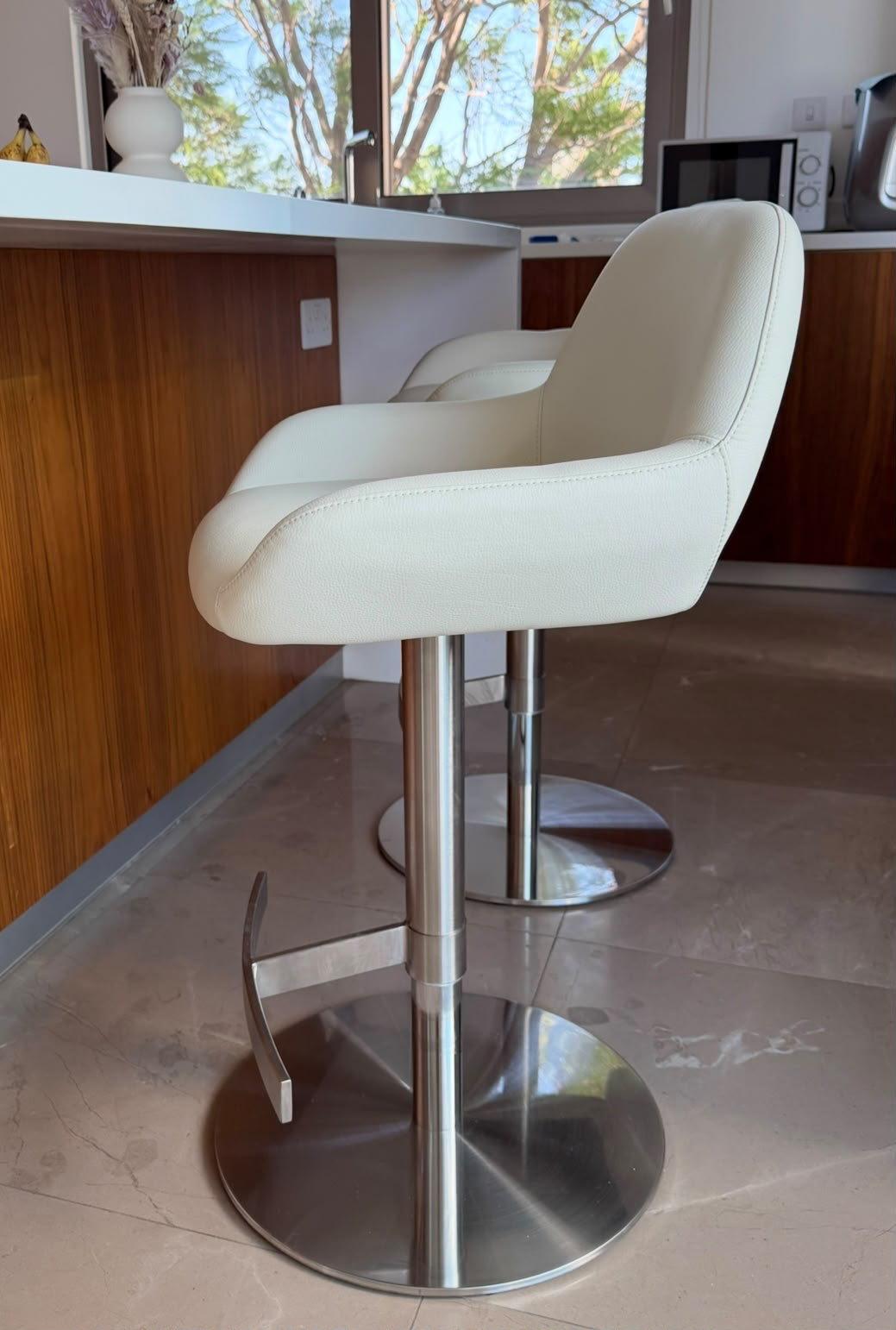 Side view of cream leather swivel stools against walnut cabinetry