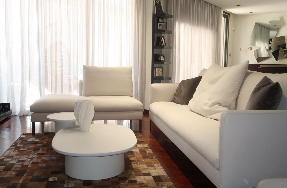 Living room with pale linen sofa, sheer curtains and round coffee tables