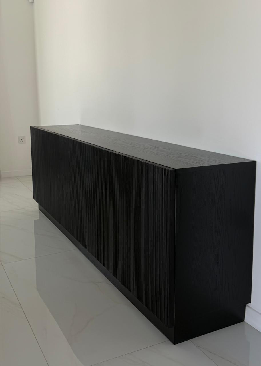 Angled view of the fluted black sideboard showing its recessed plinth