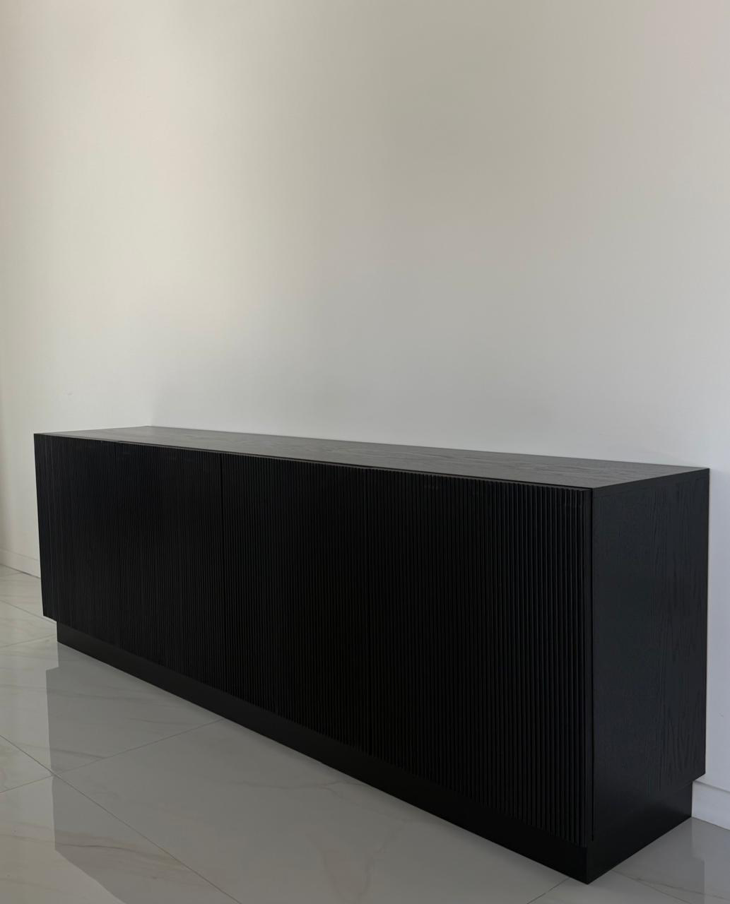 Long fluted black oak sideboard against a white wall